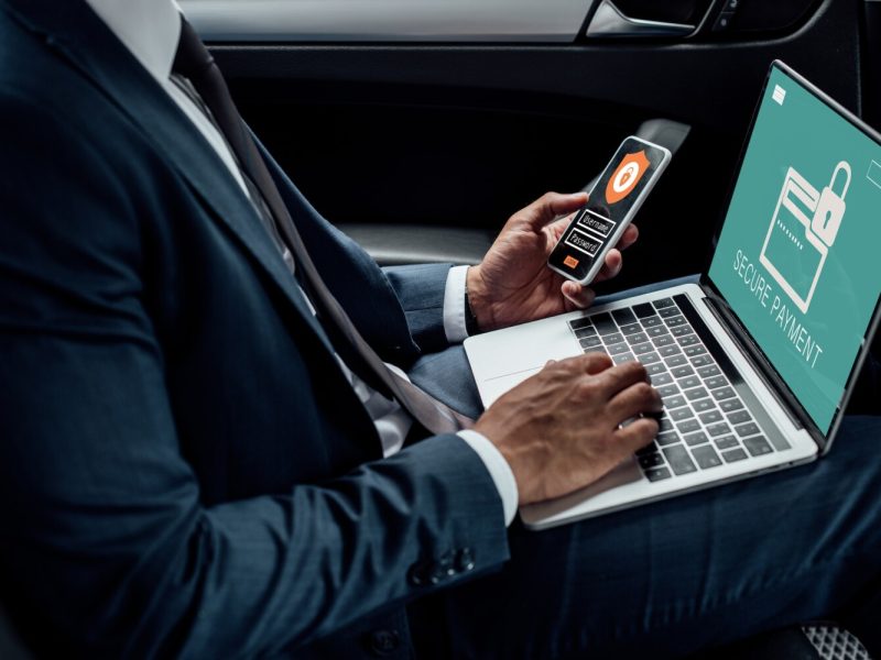 cropped-view-of-african-american-businessman-using-laptop-and-smartphone-in-car-with-cyber-security.jpg